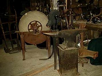 large photo of vintage blacksmith tools, including anvil, bellows and vise